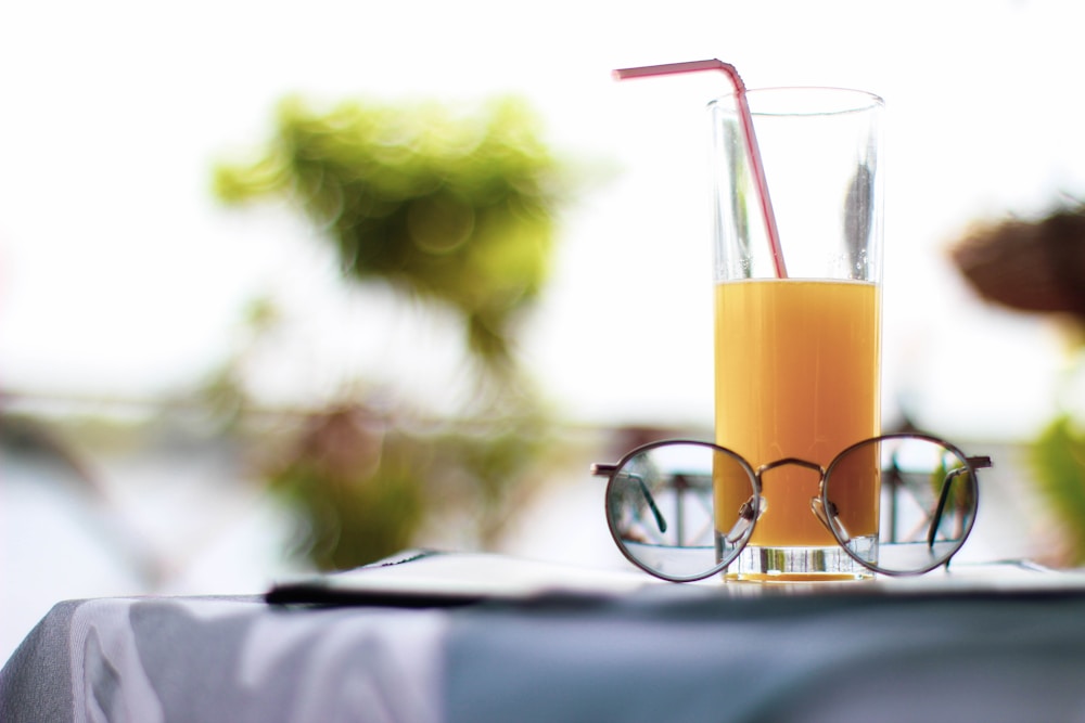 Un verre de jus d'orange et une paire de lunettes de soleil sur une table