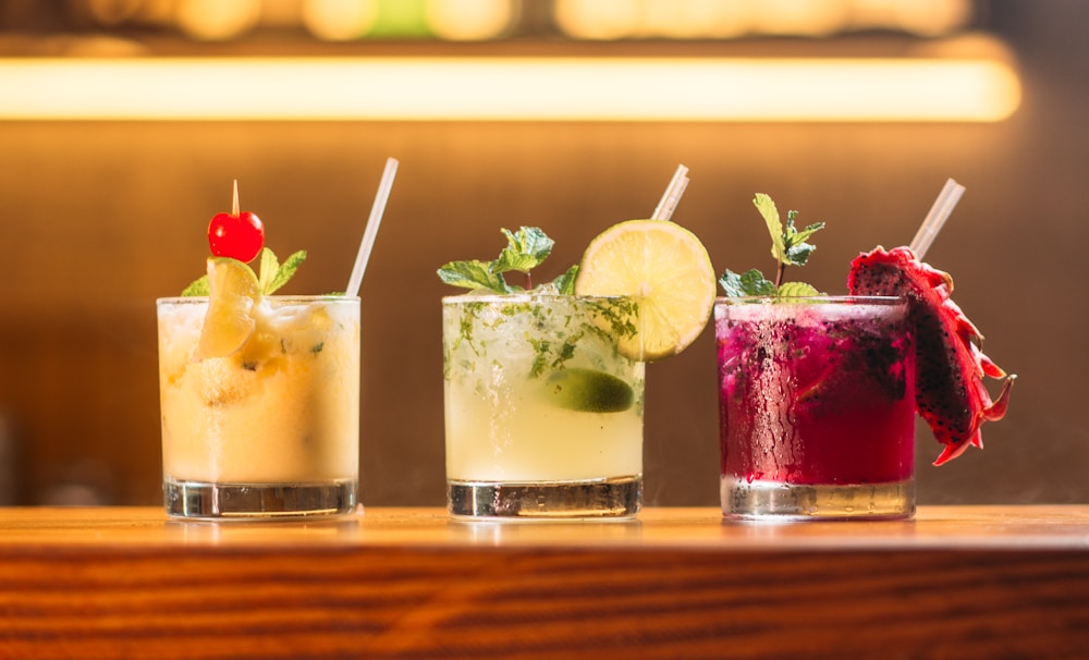 Trois cocktails colorés alignés sur un comptoir
