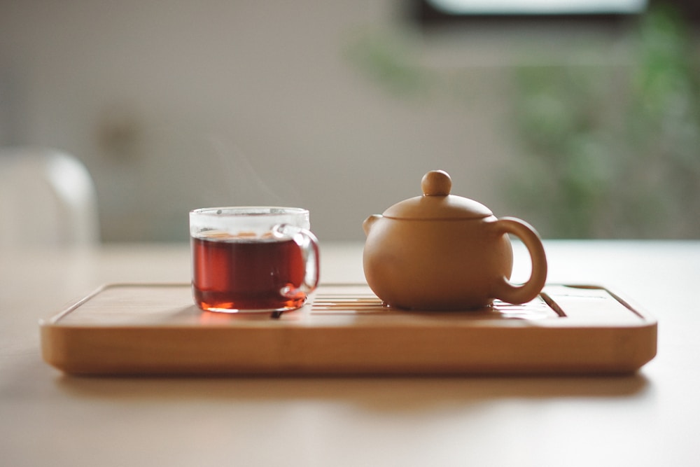 Un service à thé et une tasse de thé posés sur un plateau en bois